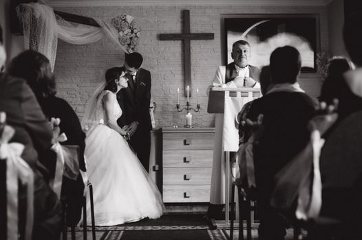 A romantic black and white photo of a wedding ceremony in a church setting.