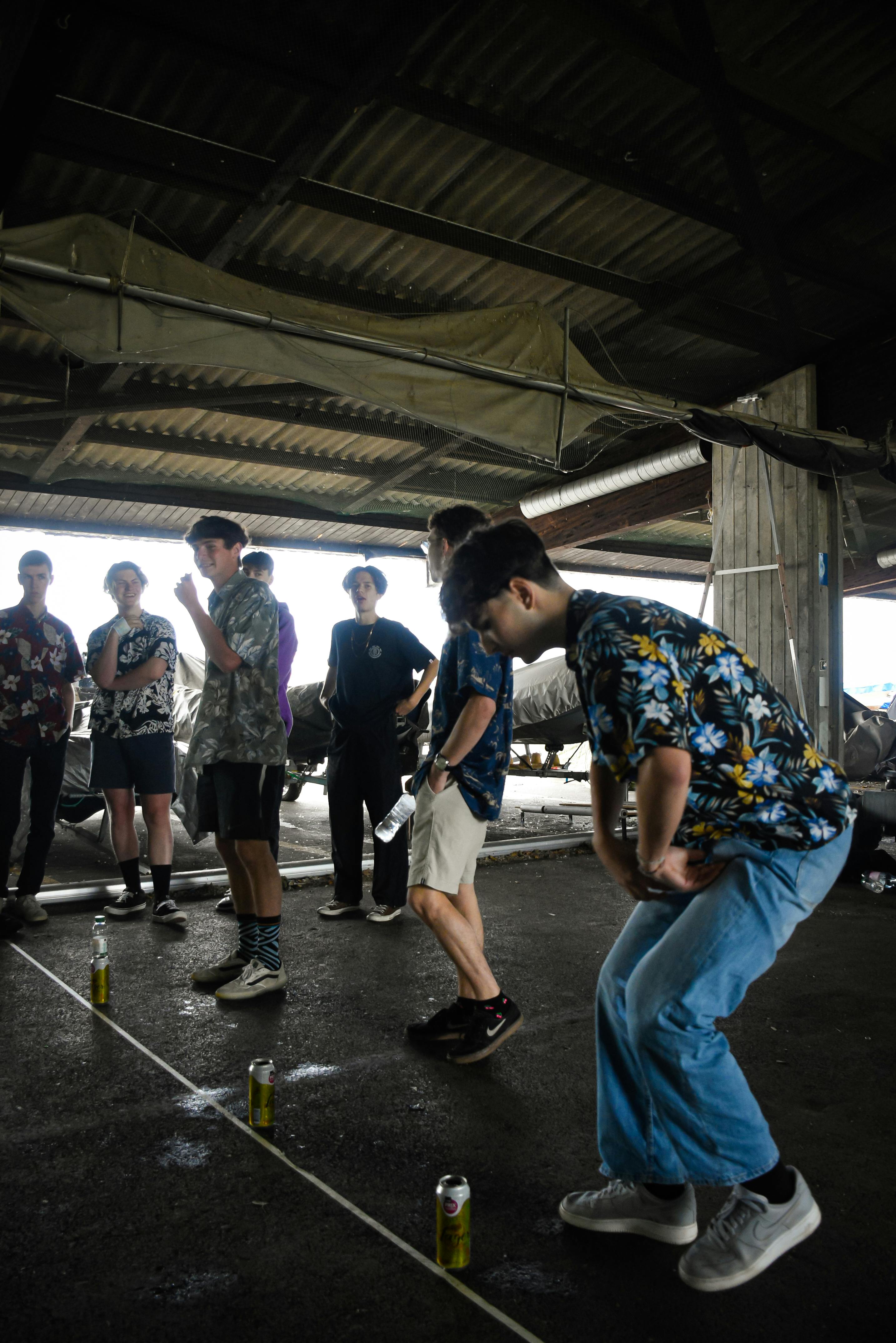 Casual group of teenagers playing an indoor can game in an industrial setting.