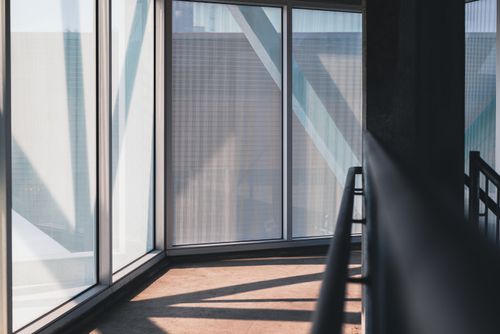 Free Sunlit modern corridor with large windows and metal railings offers a serene architectural view. Stock Photo