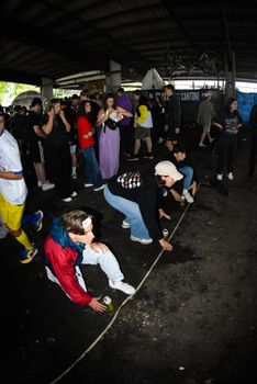 Group of people participating in an energetic game under a covered structure.