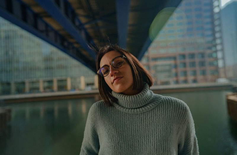 Woman in a turtleneck sweater and glasses by the water