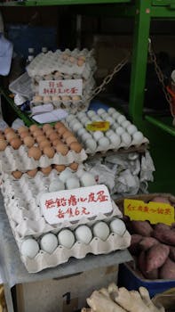Assorted eggs and sweet potatoes for sale at a local market, featuring signs in Chinese script.