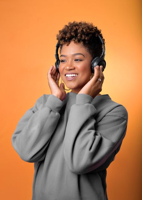 A woman listening peacefully with headphones in a bright relaxed setting, the listening cadence that fits a long walk or a quiet evening with a pet.