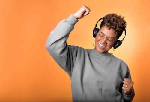 Woman in Gray Long Sleeve Shirt Dancing to Music