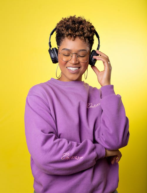 Woman Touching Her Headphones while Smiling