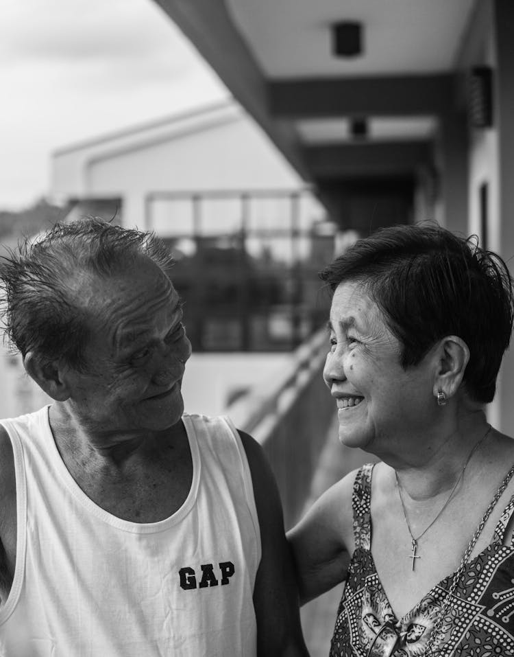 An Elderly Couple Smiling At Each Other