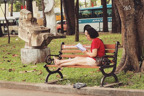 無料 ベンチに座っている赤いシャツの女性 写真素材