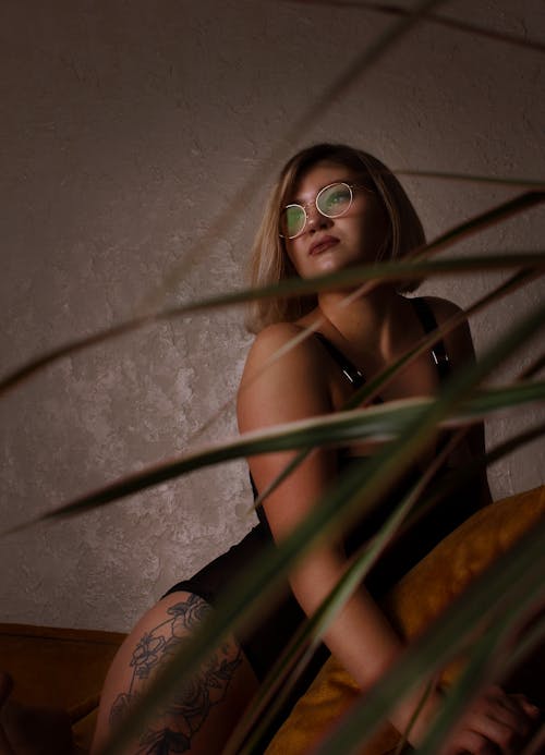 Photo of a Woman with Eyeglasses Posing Near Green Leaves