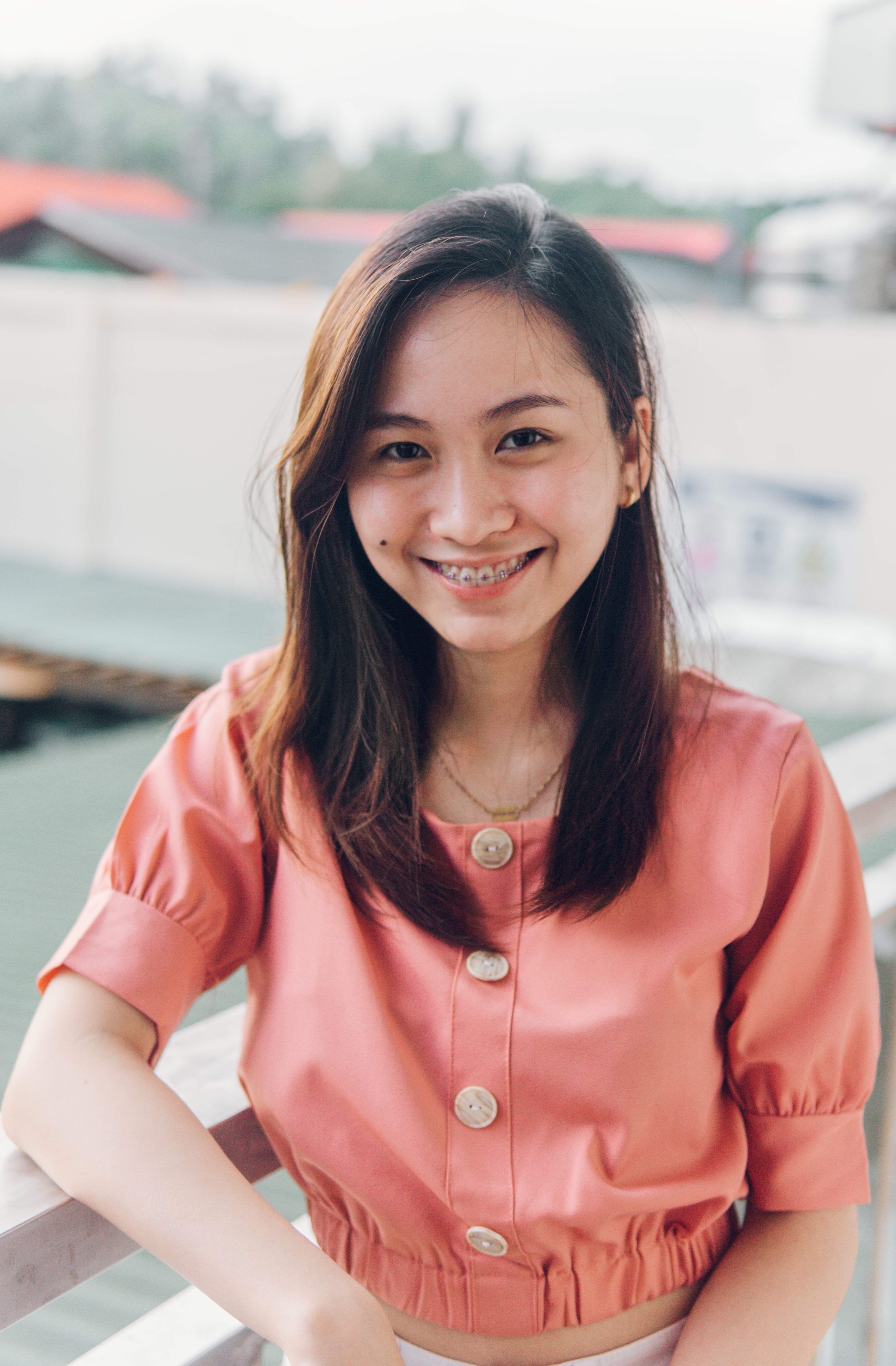 Portrait of a smiling young woman wearing a pink blouse outdoors. Bright and cheerful vibe.