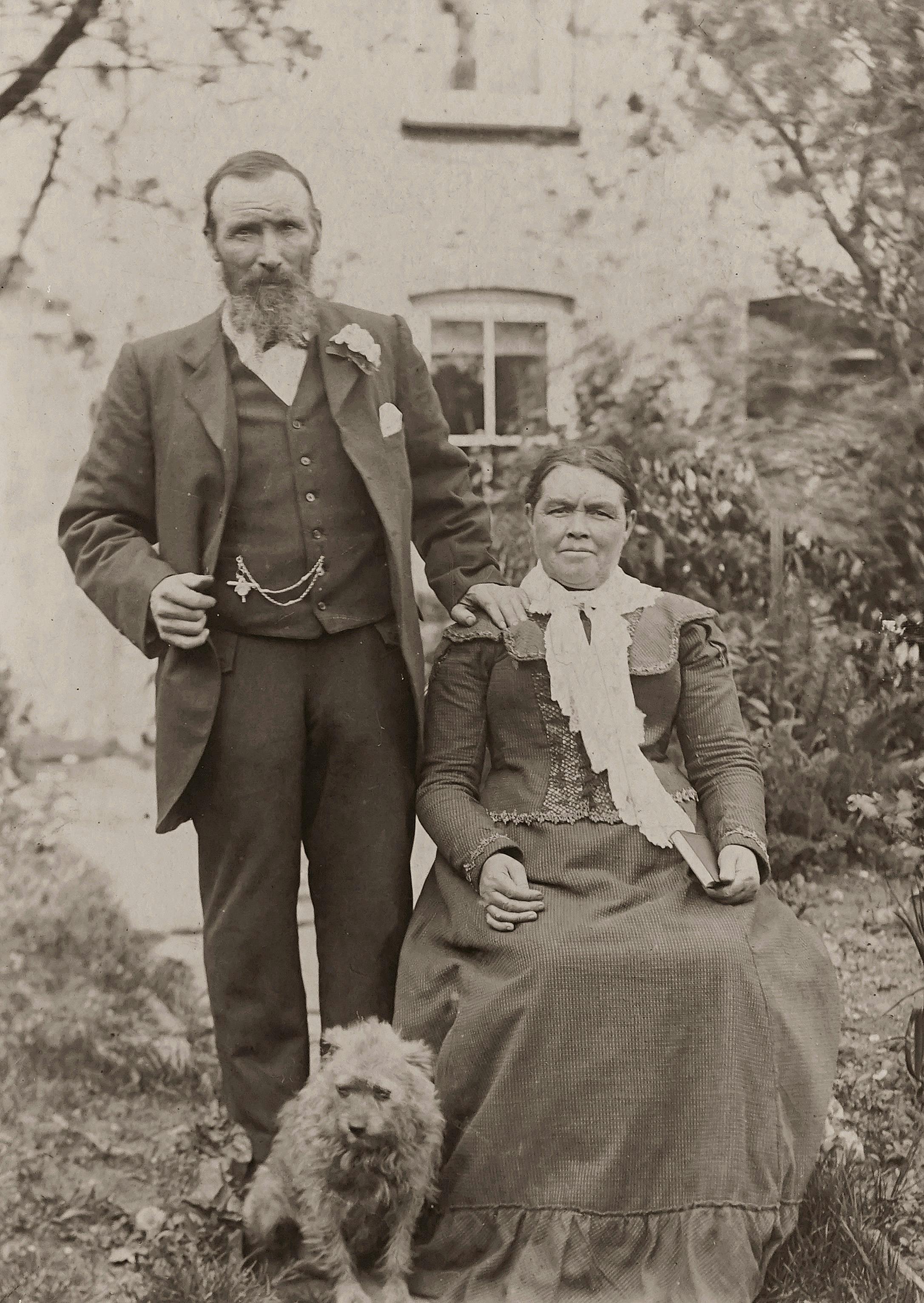Classic sepia portrait of an elderly couple with a dog, outdoors in a garden