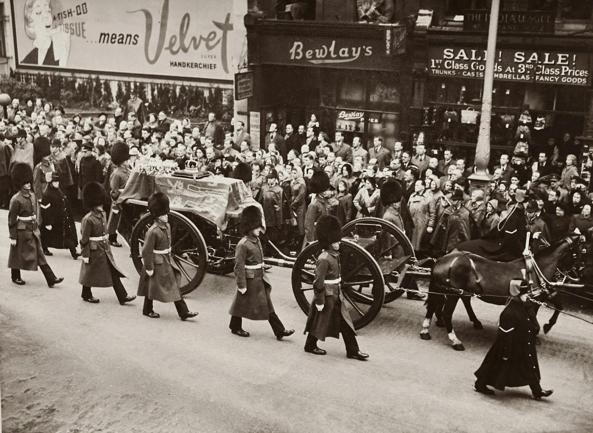 Grayscale Photo of A Funeral Procession Accompanied By Soldiers on Street