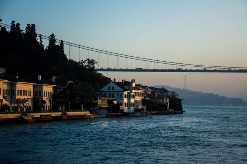 Free Scenic view of the Bosphorus Bridge and waterfront houses in Istanbul during sunset, capturing the tranquil evening ambiance. Stock Photo