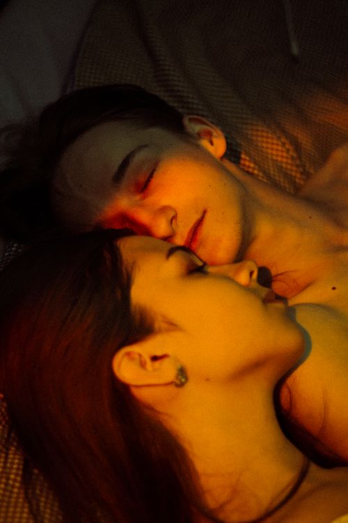 Free A couple in a tender embrace lying together, captured in warm, intimate lighting. Stock Photo