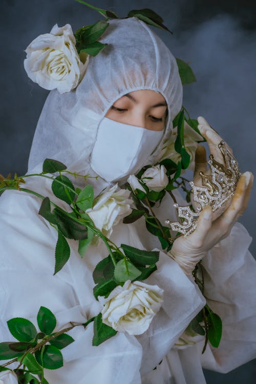 Woman Wearing Personal Protective Equipment Looking at the Crown she is Holding