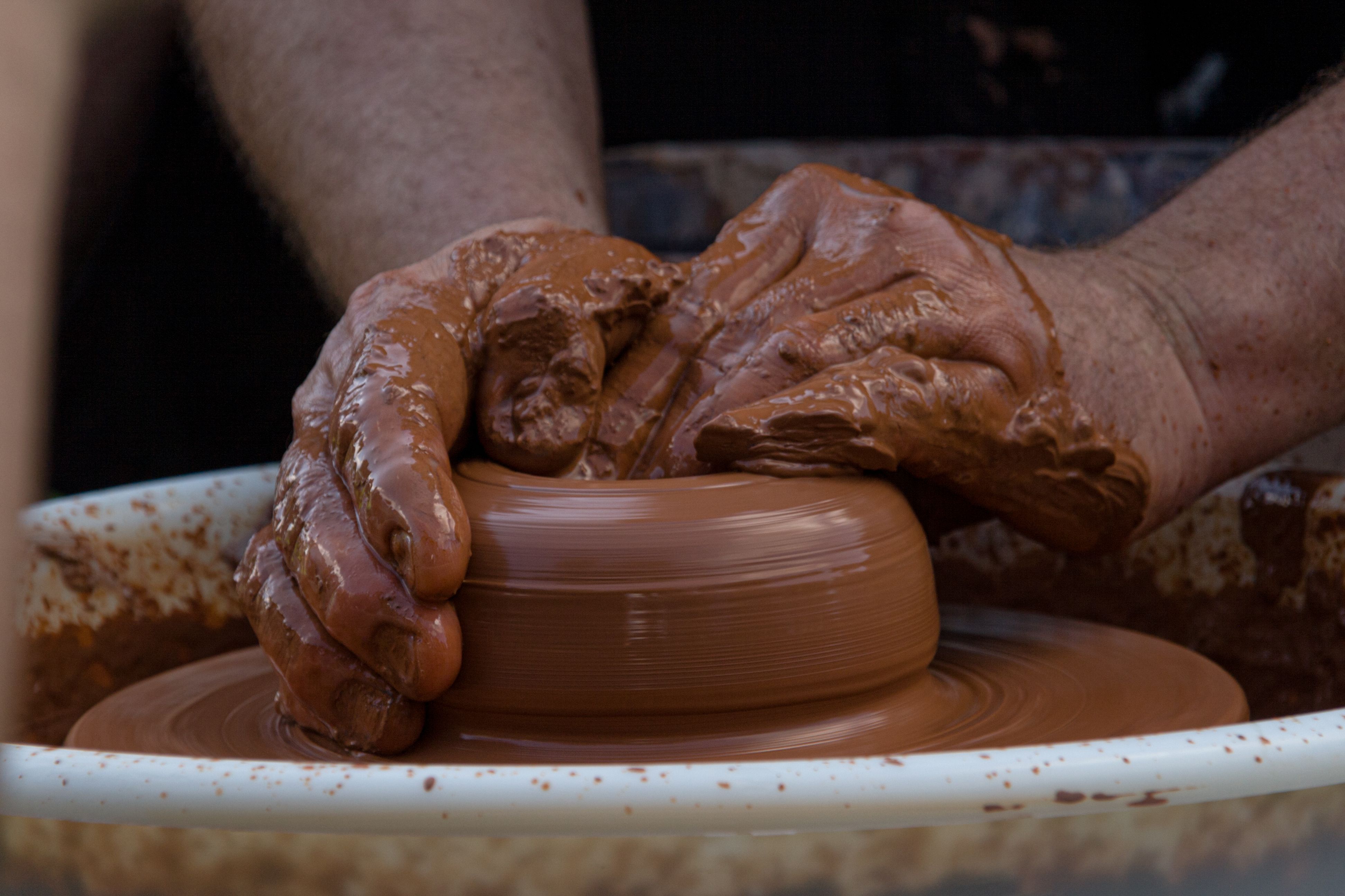 Artisan hands skillfully shaping pottery on a wheel, showcasing the craftsmanship of handcraft and clay work.