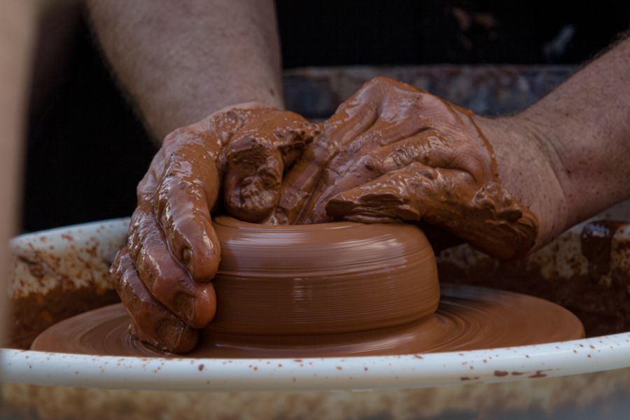 Hands shaping wet red clay during the making of Column Vase No. 9
