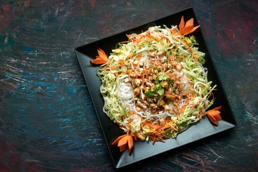 Colorful Vietnamese salad with fresh vegetables on a black square plate, perfect for healthy eating.