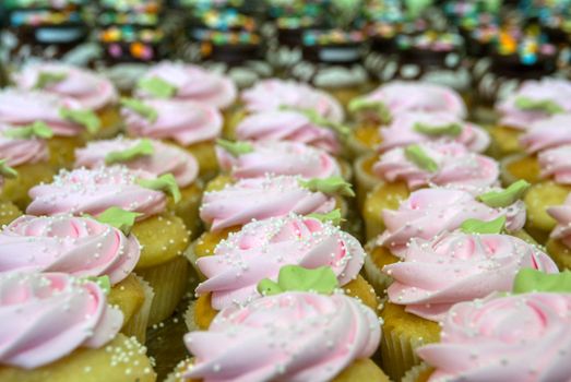 Close-up view of pink frosted cupcakes with sprinkles, perfect for dessert indulgence.