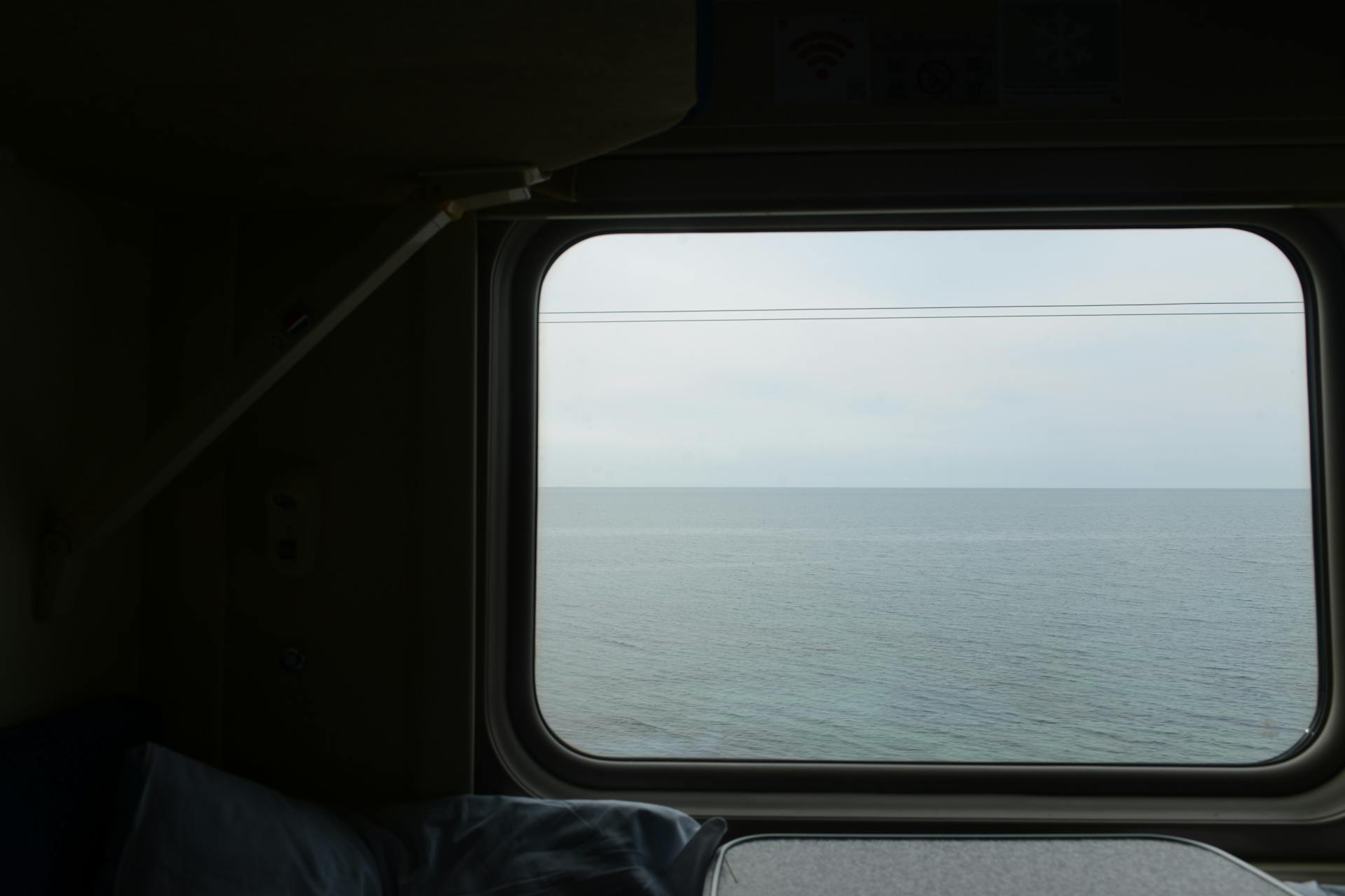 A tranquil view of the sea from a train window, capturing peaceful travel vibes.