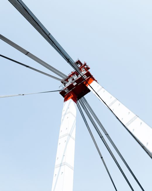 Low angle shot of a modern suspension bridge with steel structure against a clear sky.