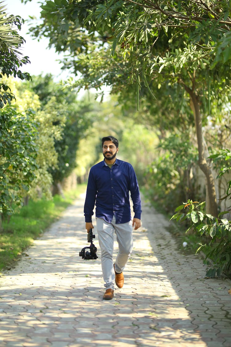 Man Walking On The Pathway Surrounded By Trees