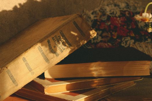 A stack of vintage books in warm sunlight casting intricate shadows, evoking nostalgia.