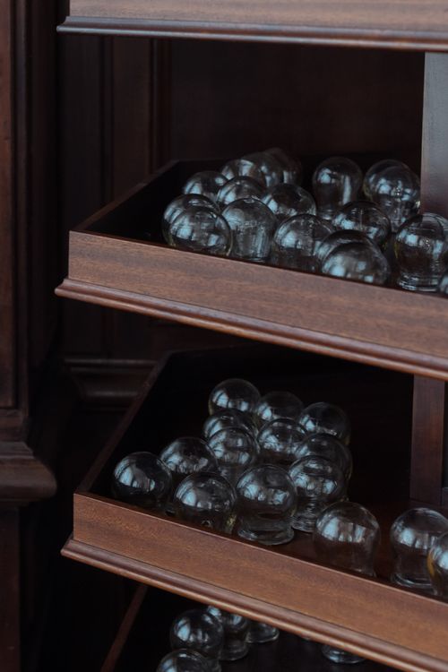 Free Glass cupping therapy tools organized on wooden shelves in an indoor setting. Stock Photo