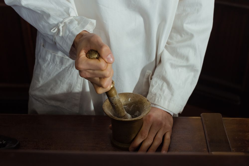 Farmacéutico majando una preparación en el mortero del laboratorio