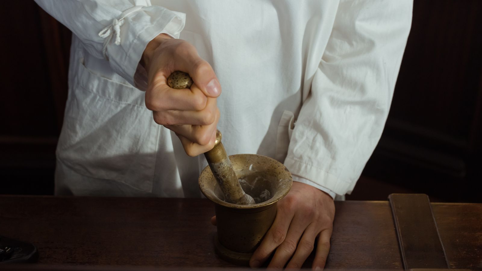 Pharmacist grinding ingredients using a mortar and pestle. Traditional pharmacy preparation.
