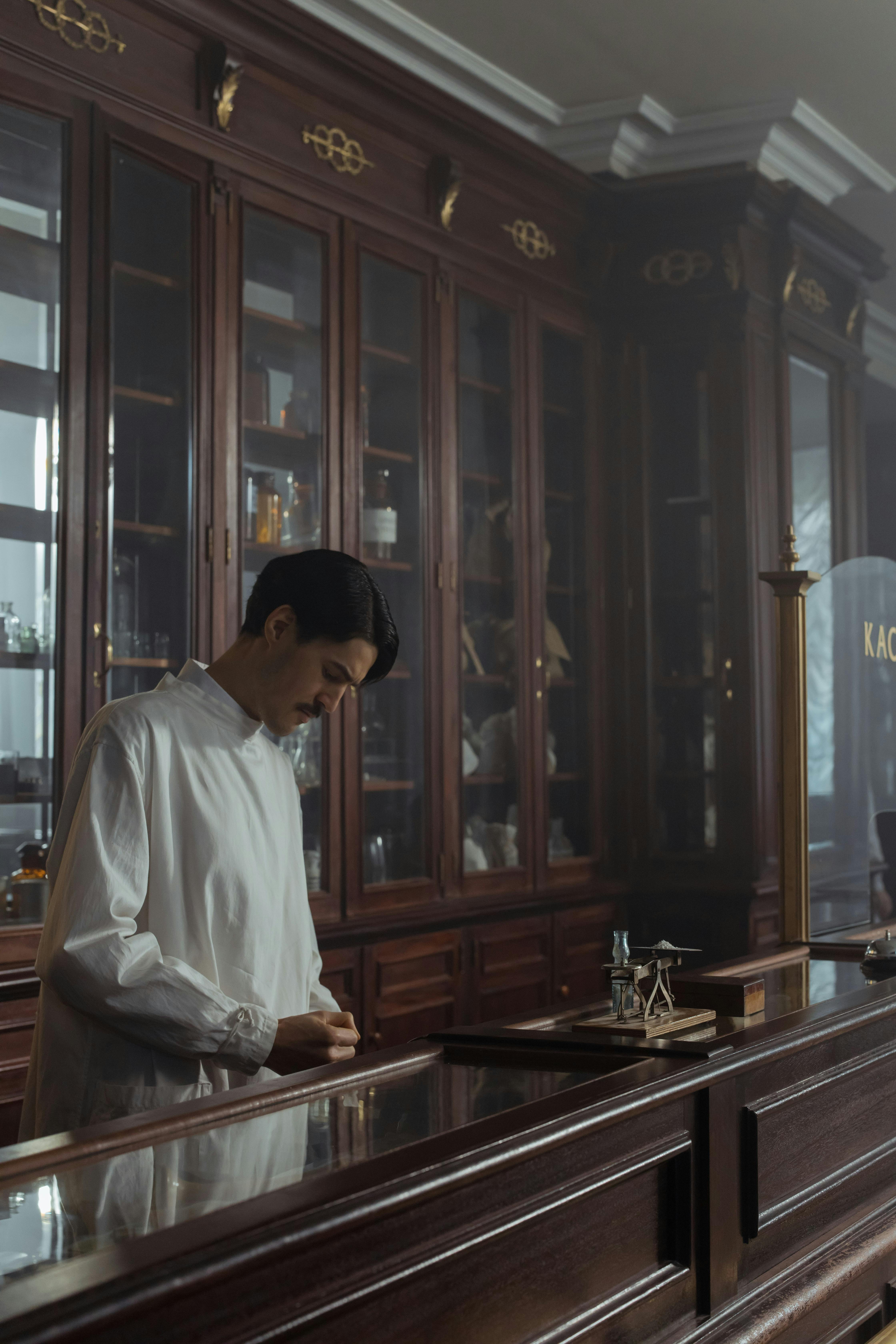 pharmacist in a white gown standing behind the counter in a vintage pharmacy