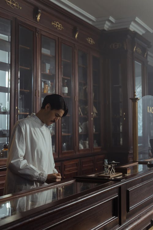 Pharmacist in a White Gown Standing behind the Counter in a Vintage Pharmacy 