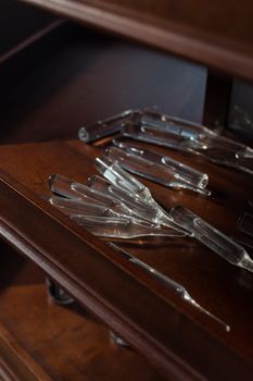 Cluster of glass ampoules on a wooden shelf in a pharmacy setting.