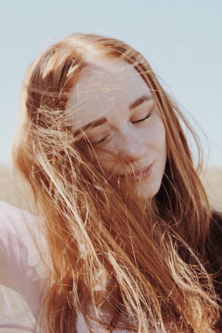 Gentle portrait of a woman with closed eyes enjoying a sunny day with the wind in her hair.