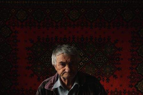 Free Portrait of an elderly man with rich cultural tapestry background, evocative and warm. Stock Photo