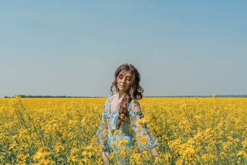 A Pretty Woman Standing on a Field of Yellow Flowers
