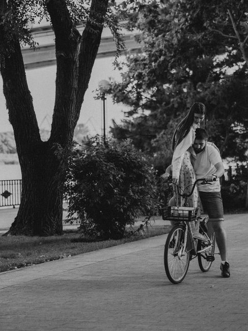 A black and white photo of a couple enjoying a romantic bicycle ride in a park.