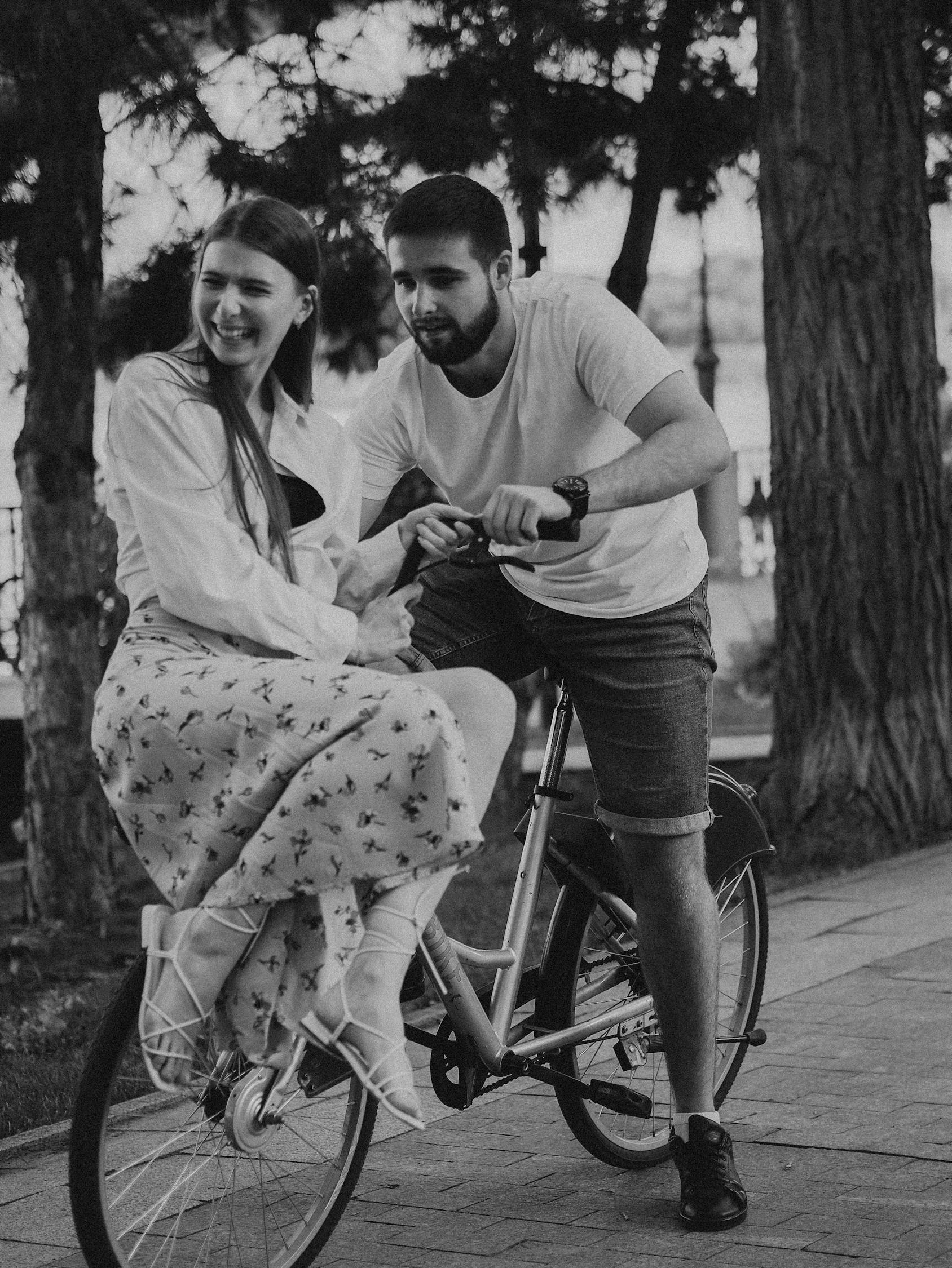 Man and Woman Riding on Bicycle in Grayscale Photography