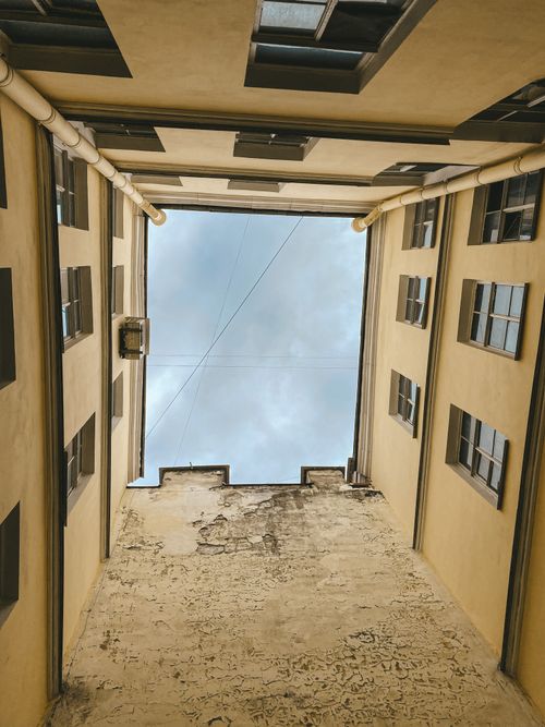 Free Worm's eye view of narrow alley between buildings with visible sky. Stock Photo