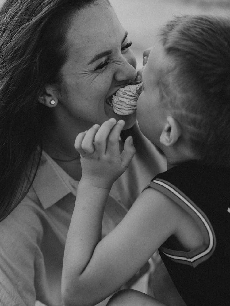 A Mother And Child Biting A Food Together