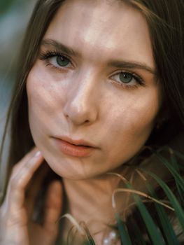 Striking close-up portrait of a woman with natural lighting casting patterns on her face.