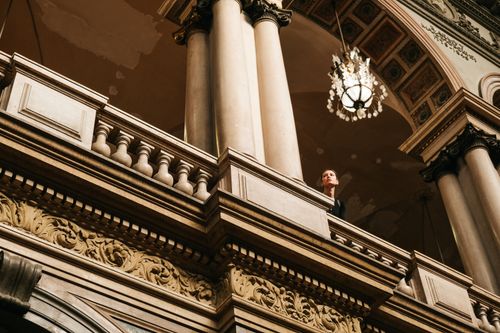 Free Ornate classic interior architecture with a woman on a balcony, highlighting arches and chandeliers. Stock Photo