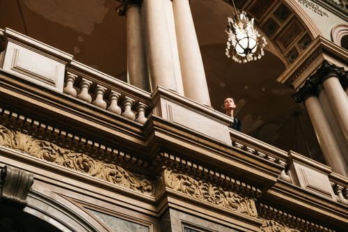 Free A low angle view of a historical balcony with luxurious carvings and ornate pillars under warm lighting. Stock Photo
