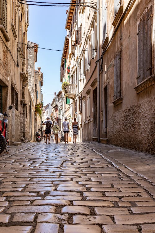 People Walking on Alley Between Apartment Buildings