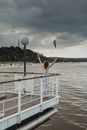 Woman in Brown Shirt and Black Shorts Jumping on White Metal Railings Near Sea