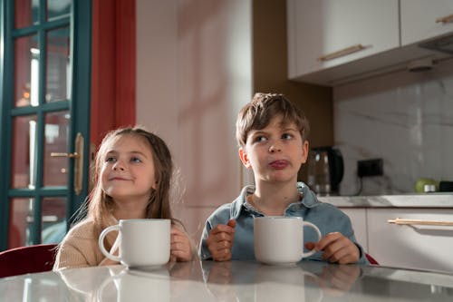 Free Girl and Boy Sitting at the Table Stock Photo