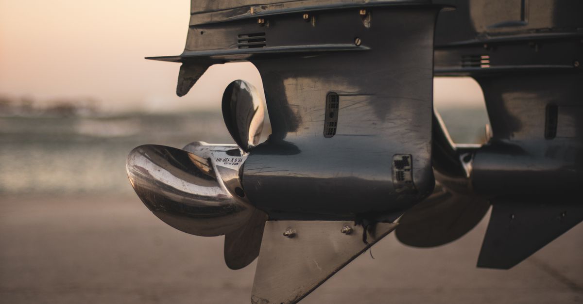 Detailed close-up of stainless steel boat propellers at sunset by the waterside.