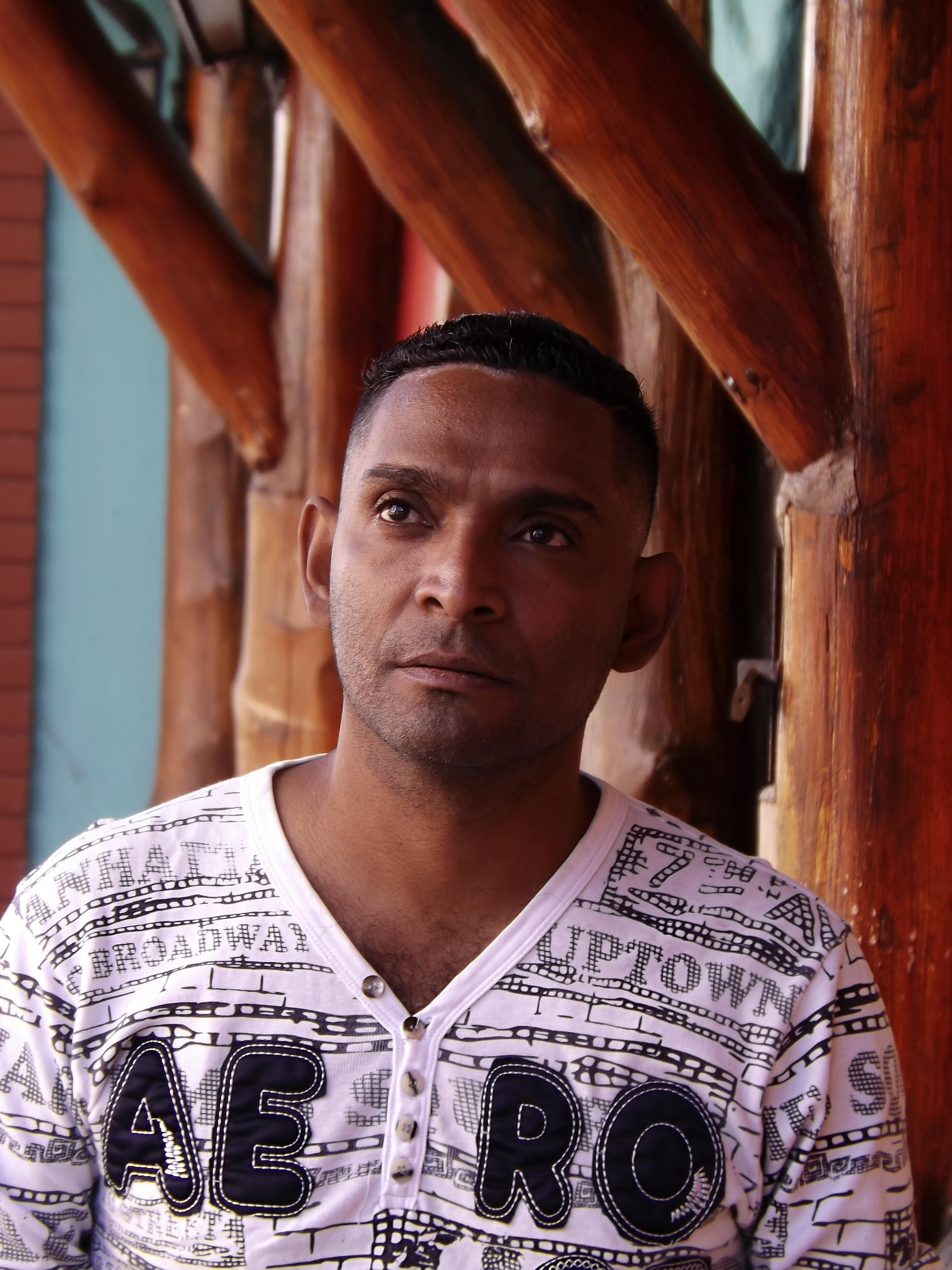 Portrait of a man looking away, set against a wooden backdrop in Venezuela.