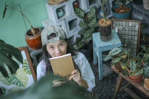 High-Angle Shot of a Woman with a Green Cap Holding a Notebook