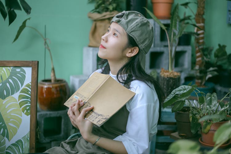 Photo Of A Girl Holding A Book While Looking Up