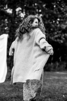 Monochrome image of a woman wearing a sweater, captured outdoors with a natural backdrop.